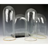 Four Victorian blown glass domes one with an ebonised base on turned feet, the tallest 20½in. (