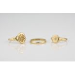 Two 18ct gold signet rings and an 18ct gold wedding band. (3)