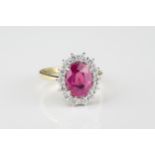 An 18ct yellow gold, pink sapphire and diamond cluster ring the 3.14ct oval cut sapphire within a