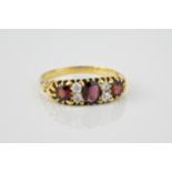 A Victorian 18ct gold, garnet and diamond ring the three oval and round cut garnets divided by pairs