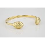 An 18ct yellow gold Torq style bangle with shell form terminals.