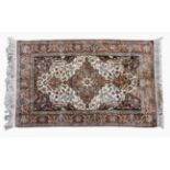 A small Persian silk rug the ivory field with central floral pendant medallion and all over floral