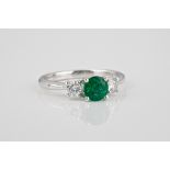 An 18ct white gold, emerald and diamond three stone ring the central 0.83ct round cut emerald