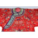 A Chinese red ground embroidered silk woman's informal robe 19th century, finely embroidered with