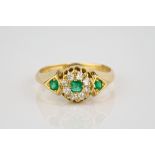 A late Victorian 18ct gold, emerald and diamond cluster ring the central emerald within a border