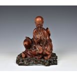 A 19th century carved boxwood figure of a seated scholar and tiger the seated figure, reading a book