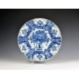 An 18th century Dutch Delft 'Peacock' pattern charger with barbed rim, painted with urn holding a