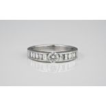 An 18ct white gold and diamond ring the central brilliant cut diamond flanked by rows of six channel