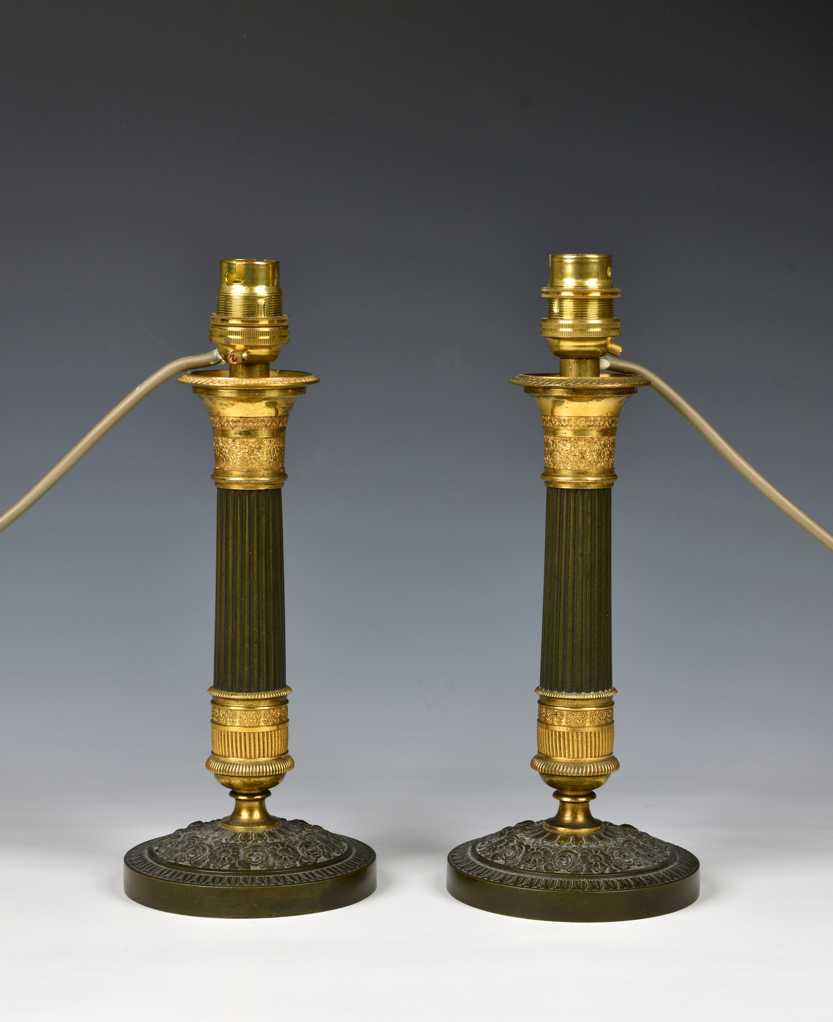 A pair of French patinated bronze and ormolu candlesticks 19th century, the tapered fluted columns