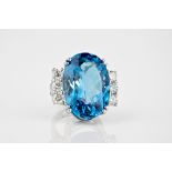 A platinum, blue topaz and diamond ring the large, 34.33ct oval cut topaz of intense blue colour,