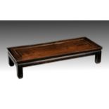 A Chinese carved hardwood opium table 19th century, the cleated panelled rectangular top raised on