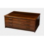 A 1920s oak three drawer plan chest with panelled sides, wooden bracket handles and brass name