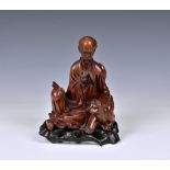 A 19th century carved boxwood figure of a seated scholar and tiger the seated figure, reading a book