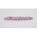 An 18ct white gold, pink sapphire and diamond line bracelet the nineteen oval cut sapphires, total