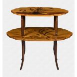 An Art Nouveau style two tier étagère in the manner of Emile Gallé the shaped oval top inlaid with a
