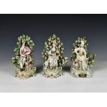 A pair of Derby porcelain seated bocage figures late 18th century, of a piper with dog and a
