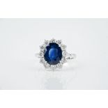 An 18ct white gold, sapphire and diamond cluster ring the 4.07ct oval cut sapphire bordered by