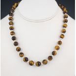 A tiger's eye and seed pearl necklace with silver and seed pearl clasp, 17in. (43.2cm.) long;