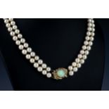 A two strand cultured pearl necklace with 14ct gold, opal and diamond clasp with 7mm. pearls, the
