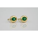 A pair of 18ct yellow gold and emerald stud earrings the oval cut emeralds in rubover settings. (2)