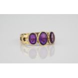 A 9ct gold and amethyst three stone ring the graduated oval cut amethysts over pierced shoulders,