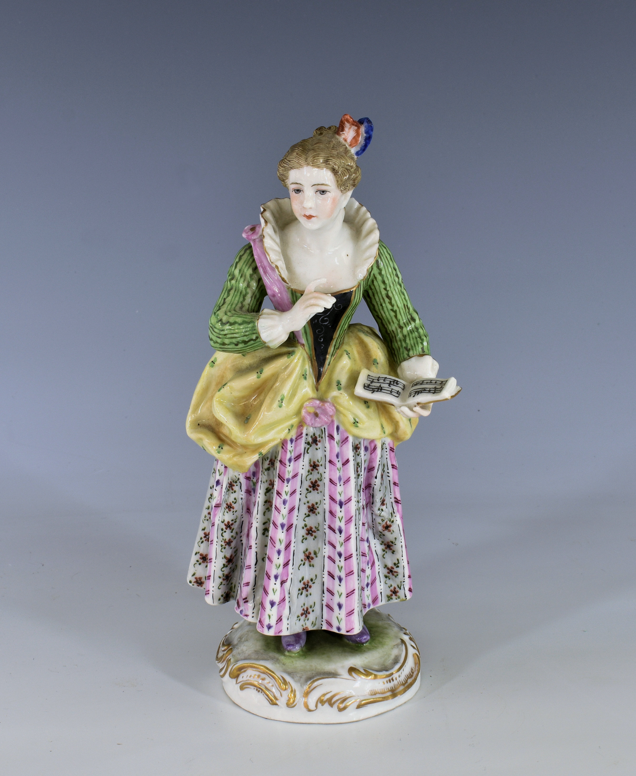 A Meissen style figure of a girl holding a music book early 20th century, Continental, in a green