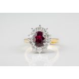 An 18ct yellow gold, ruby and diamond cluster ring the 2.03ct oval cut ruby within a border of