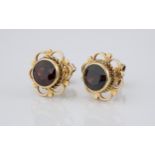 A pair of 9ct gold and garnet stud earrings the round cut garnets within a pierced floral style