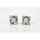 A pair of platinum and diamond flower stud earrings each set with a central brilliant cut diamond.