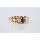 A 9ct gold, garnet and CZ three stone ring with bark textured shank, size P.