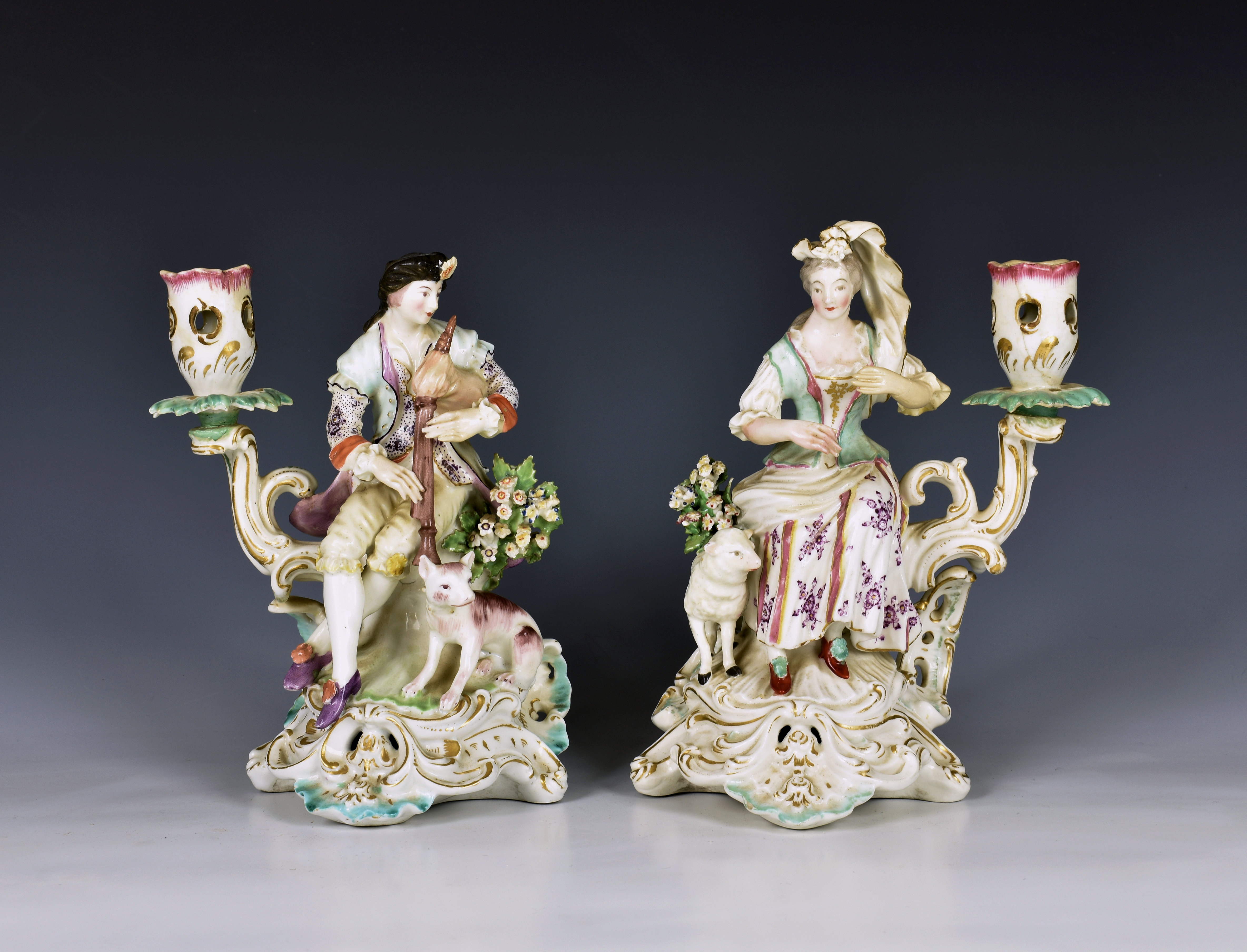 A pair of late 18th century Derby porcelain figural candlesticks the seated figures of a man playing