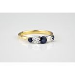 An 18ct yellow and white gold, sapphire and diamond five stone ring the three graduated round cut