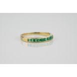 A 9ct yellow gold and emerald half eternity ring size L.