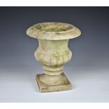 A small carved marble garden urn with turnover rim and half gadrooned decoration, on a square