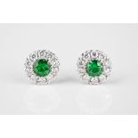 A pair of 18ct white gold, emerald and diamond cluster stud earrings the central round cut