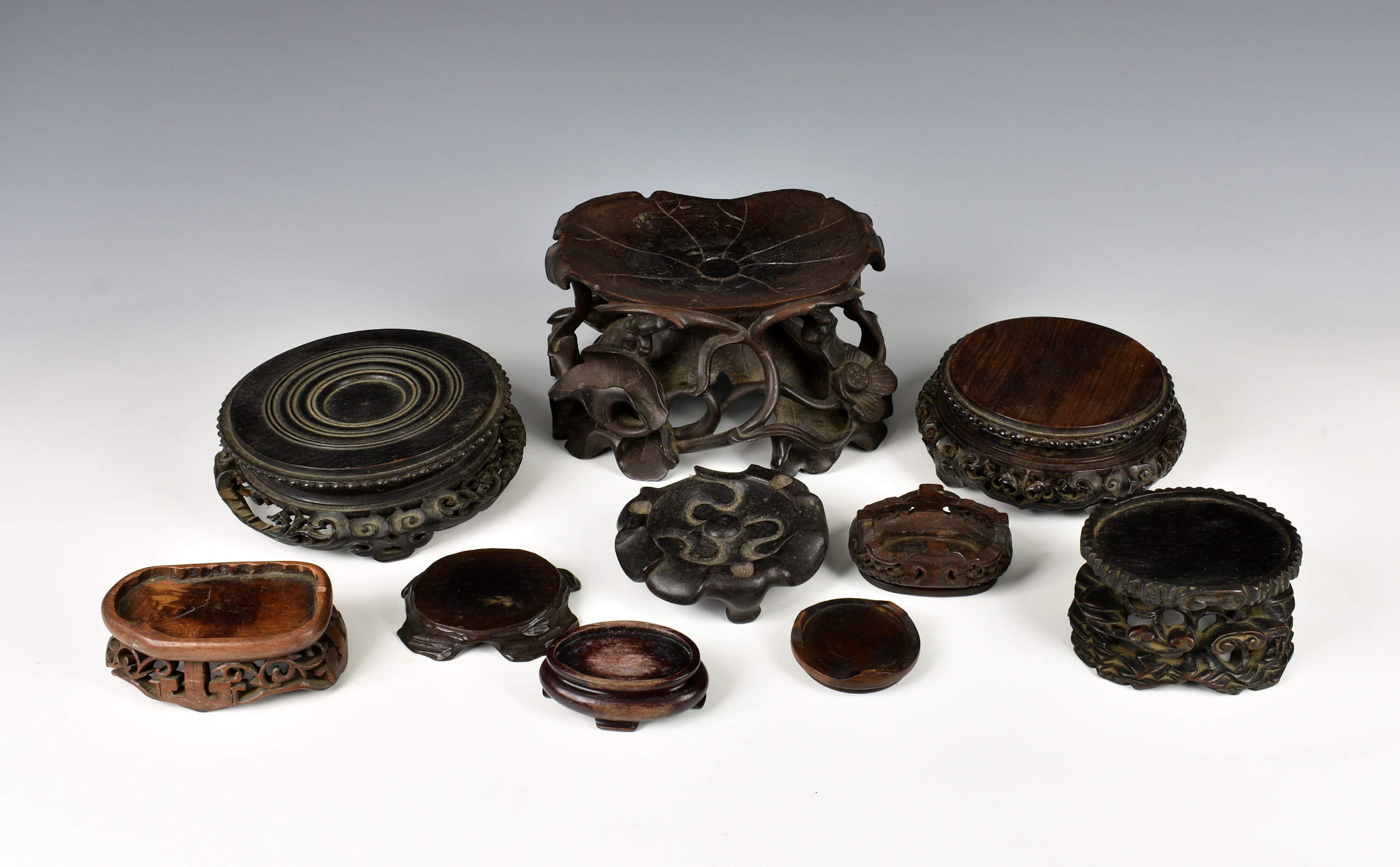 A small collection of Chinese carved hardwood stands 19th to early 20th century, the largest of