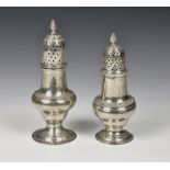 Two George III silver baluster pepper casters both of similar design, having dot pierced covers