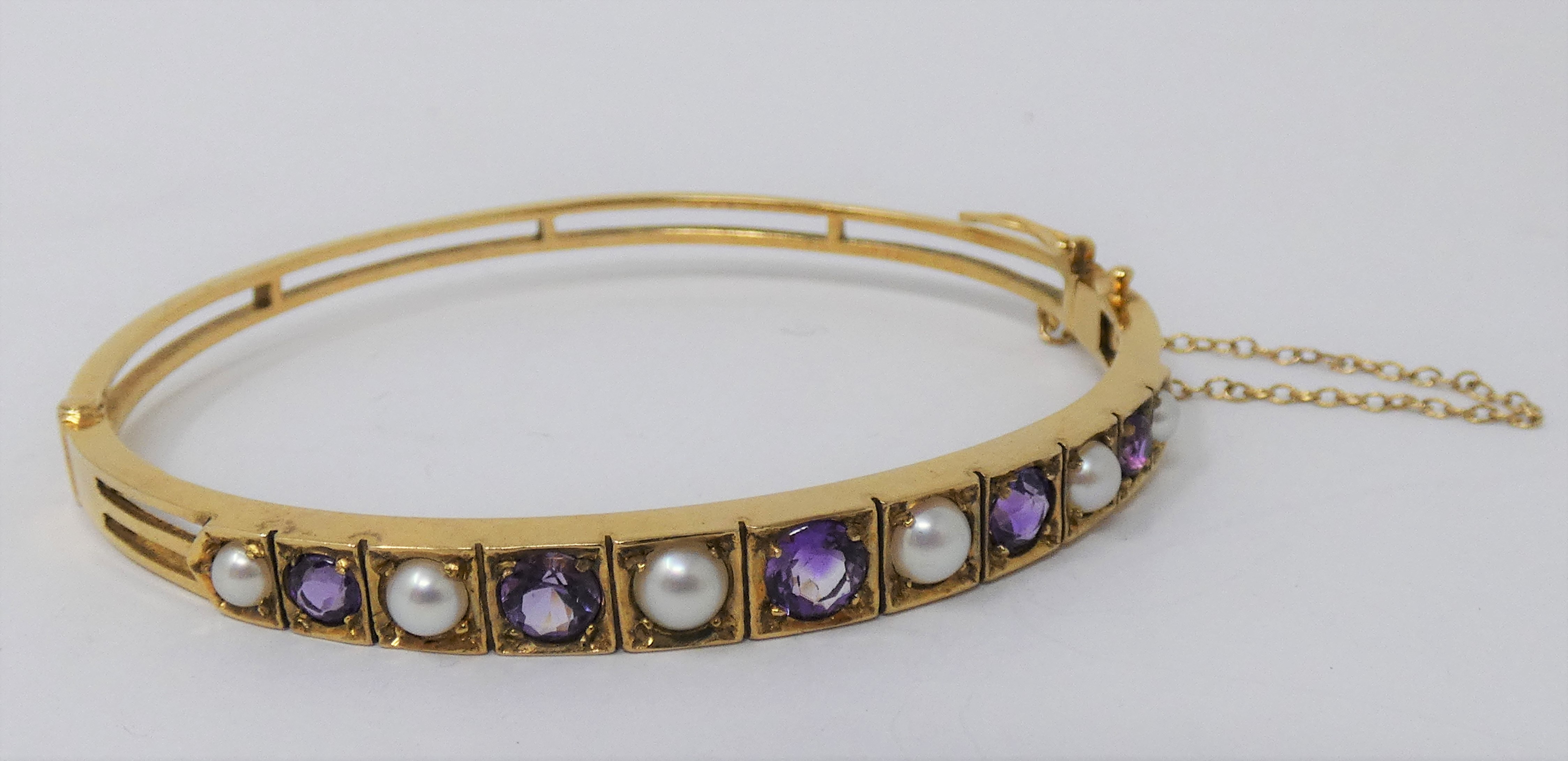 NINE CARAT GOLD AMETHYST AND PEARL BANGLE 1970s the hinged bangle set to the front with graduated - Image 2 of 2