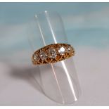 A late Victorian/Edwardian yellow metal dress ring with 5 oval graduating old cut diamonds in ornate