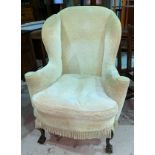 An early/mid-20th century wing back armchair in the Georgian style, upholstered in cream dralon,
