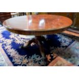 A Victorian figured mahogany dining table, with circular tilt top on turned column, triple legs