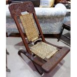 A Far Eastern folding chair in carved hardwood with cane seat