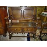 An oak Jacobean style monk’s bench heavily carved, with panelling, on bulbous column supports