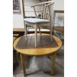 A modern light beech dining table with circular extending top; a tub shaped stick back armchair by