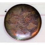 A 19th century Japanese iron saucer shaped plaque decorated in relief with a dragon in clouds,