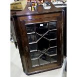 A 19th century oak wall hanging corner cupboard enclosed by single glazed door