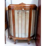 A 1950's walnut demi-lune display cabinet on ball and claw feet