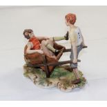 A Capodimonte group: girl in wheelbarrow, wheeled by a boy