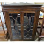 A 19th century mahogany wall hanging corner cupboard enclosed by 2 astragal glass doors