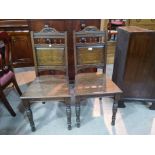 A pair of late Victorian oak panel back hall chairs